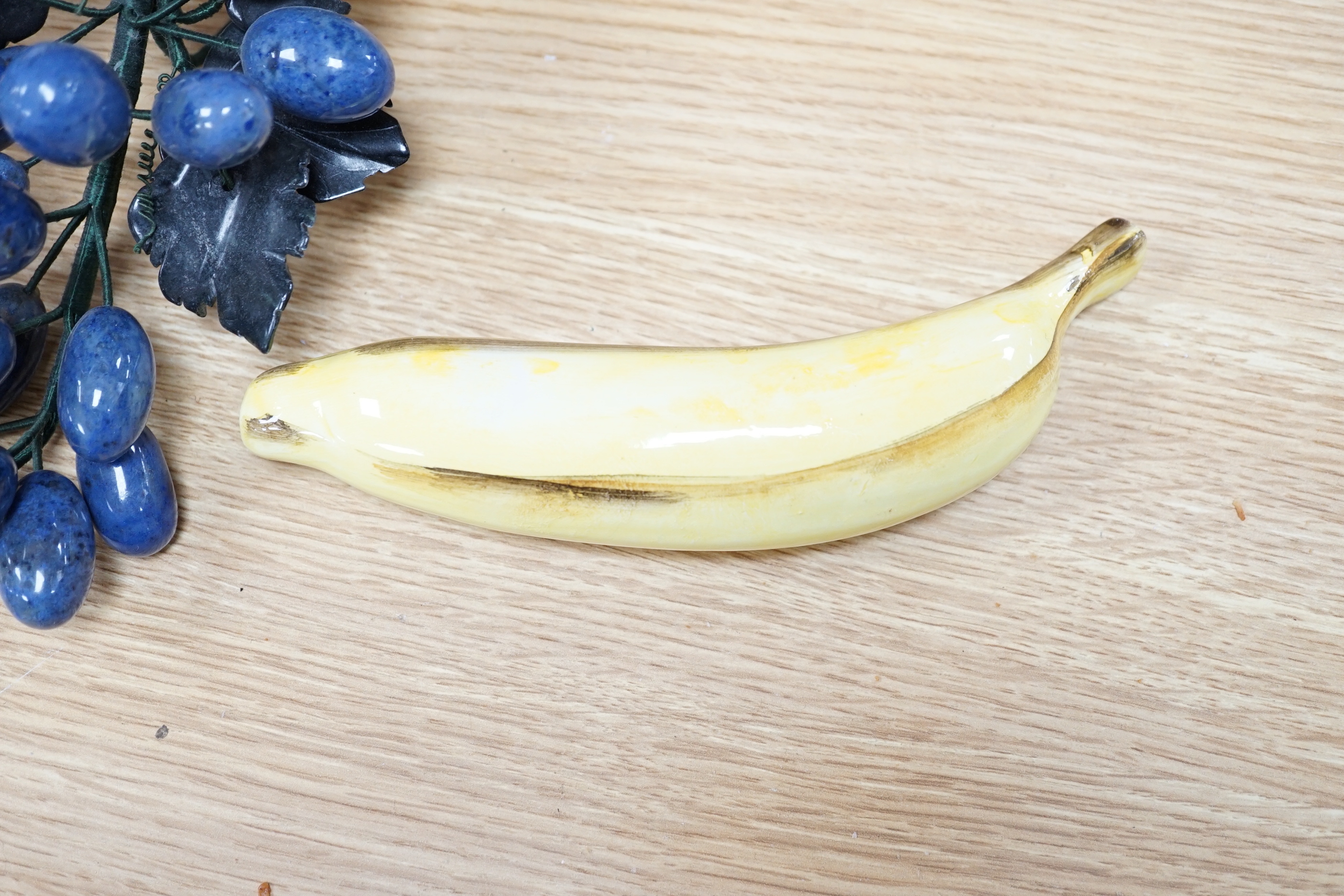 Five polished hardstone and soapstone bunches of grapes and six glazed china fruits, banana 19cm long (11)